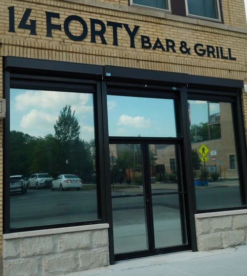 The front of 14 Forty Bar & Grill at 1440 S. Kedzie Ave.: the metal gates are open, with the windows and the front doors under the 14 FORTY BAR & GRILL sign